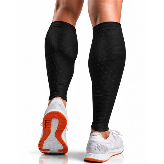 Black ribbed compression calf sleeves worn on a person's legs, shown from the back with white running shoes featuring orange soles on a clean white background.